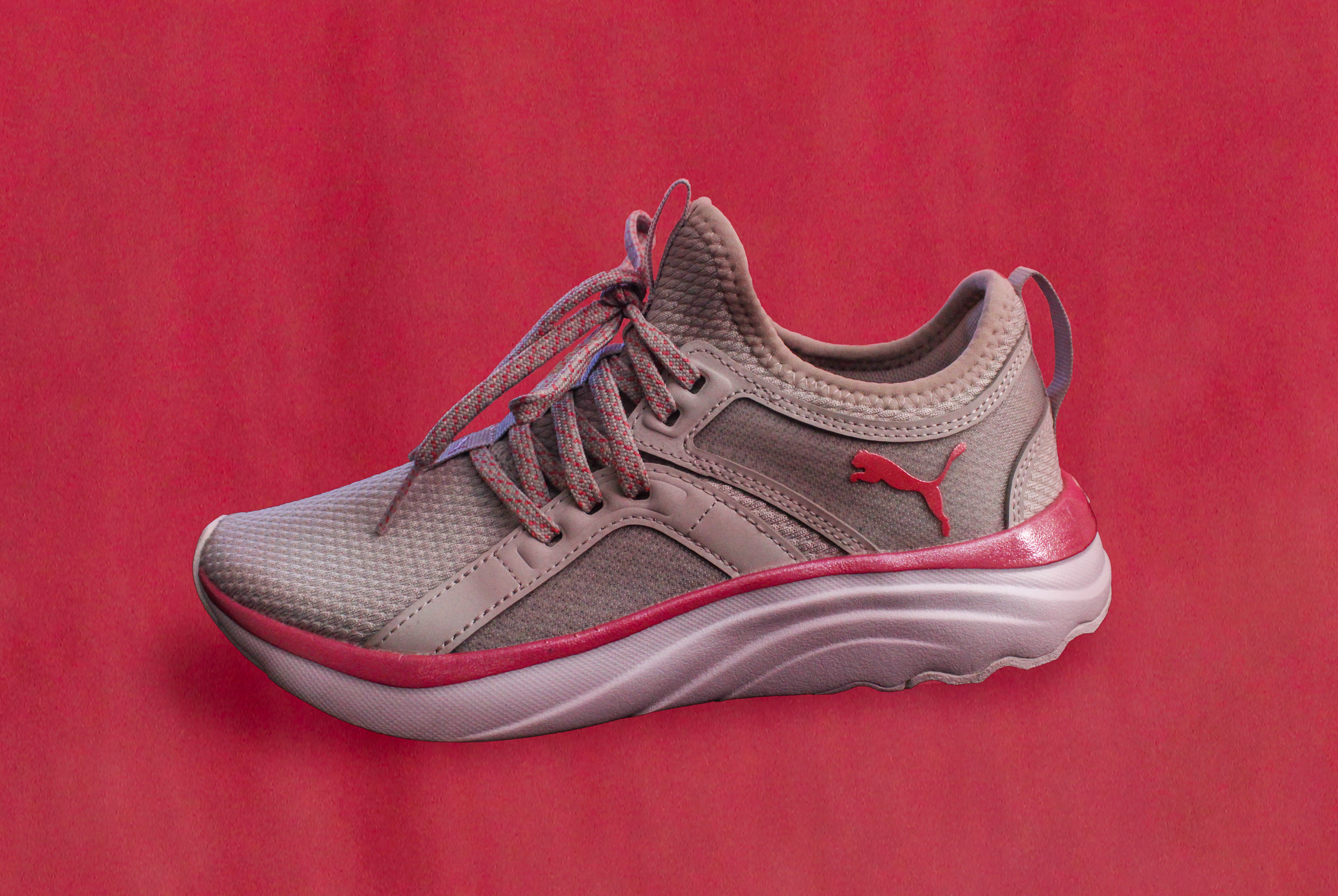 an advertisment for a brand of shoes with a singular shoe edited onto a pick background to match